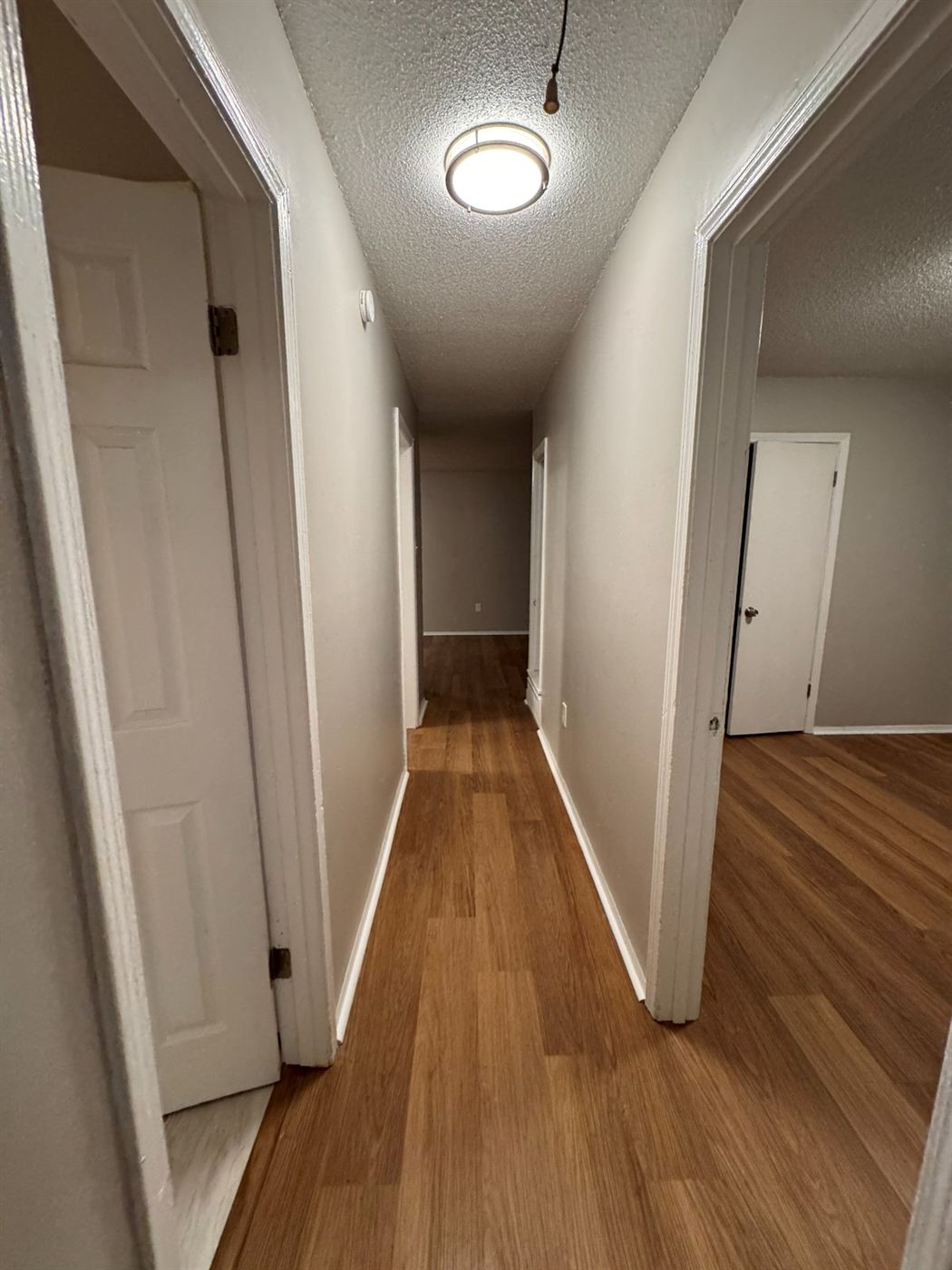 Restored hallway with new plank flooring, repaired drywall, fresh paint, and new flush-mount lighting by Delta Construction in Memphis, TN