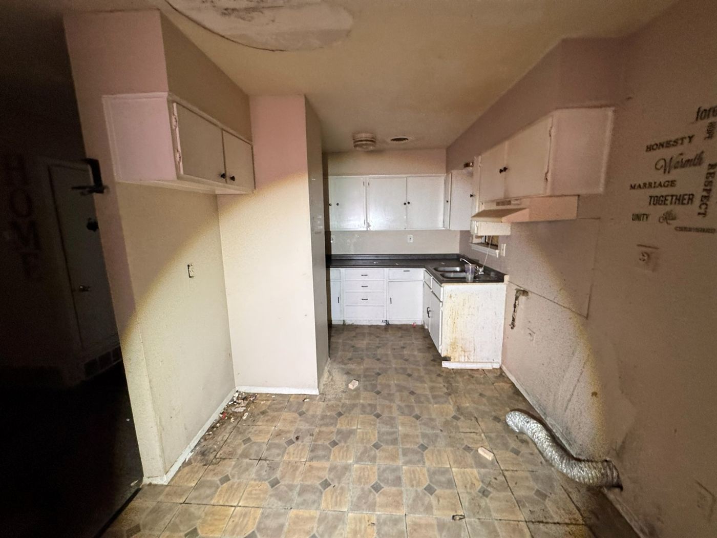 Fire and water damaged kitchen with stained bowed ceiling, blackened countertops, and worn tile flooring before restoration in Memphis, TN